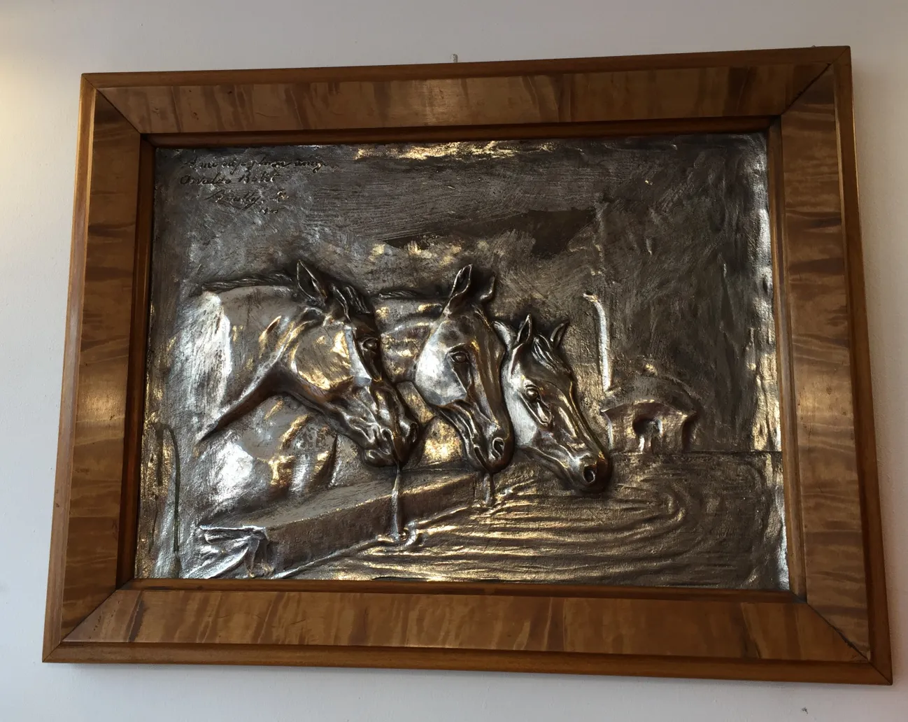 Antique wall plate featuring horse reliefs in a frame