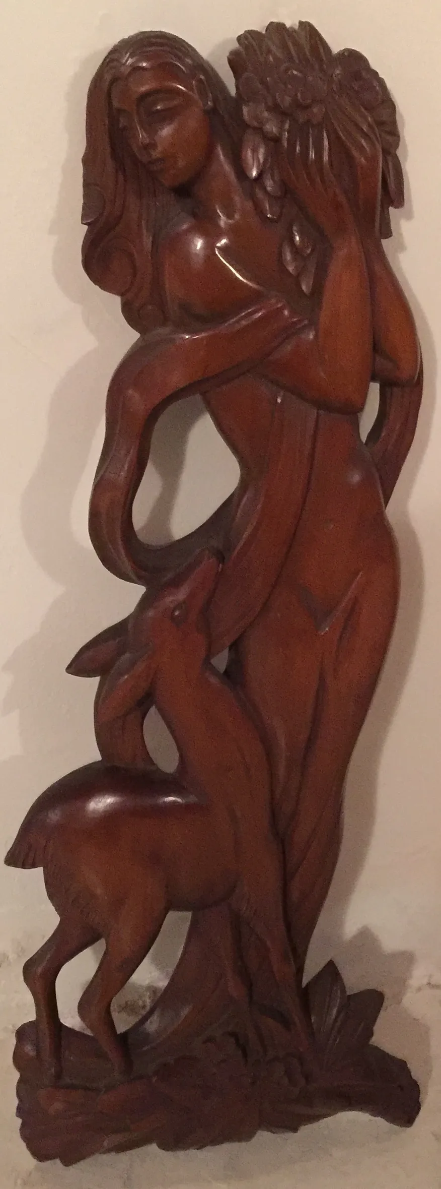 Alte Wandplatte mit Figur einer Frau, die einen Reh umarmt, in klassischer Umgebung.