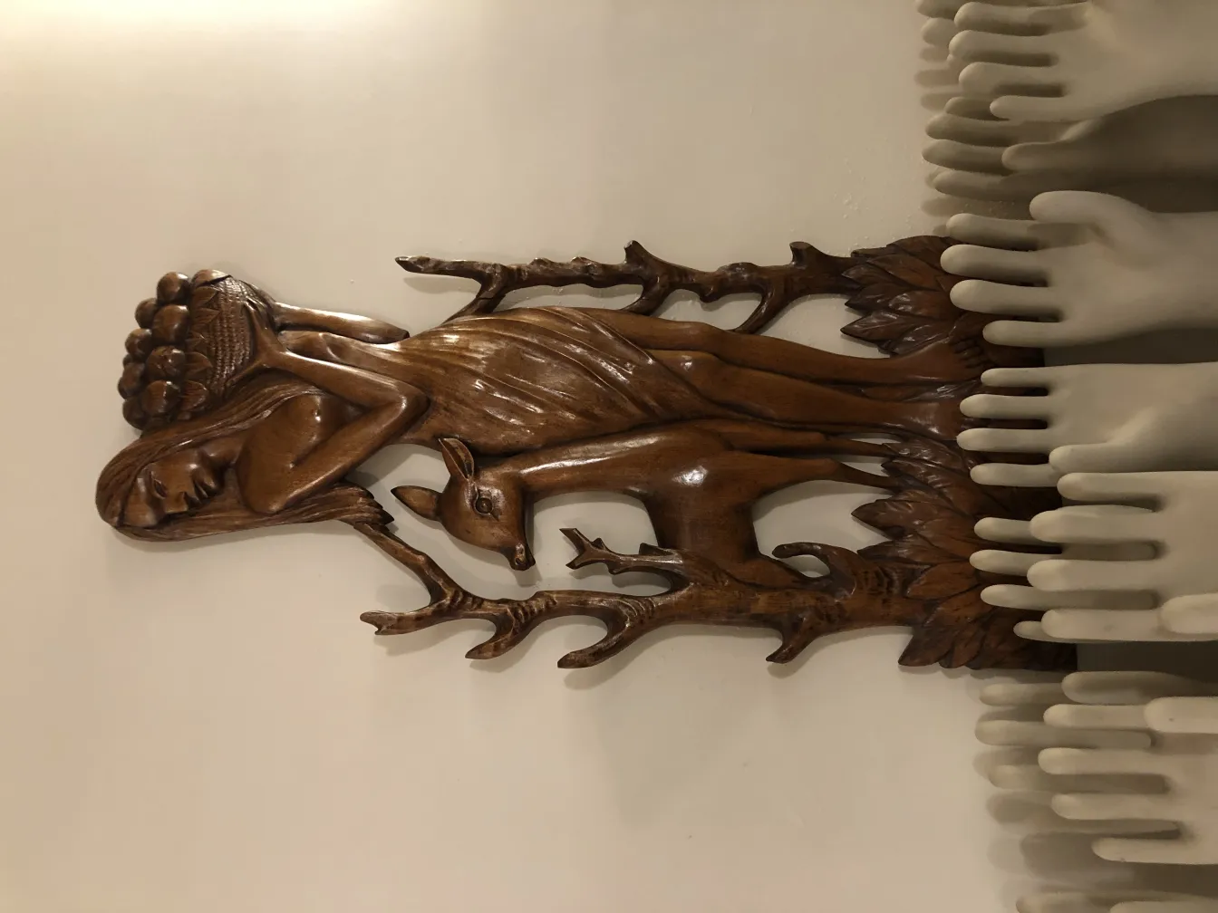 Antique wall plate with human and deer figure design, decorative in a neutral setting.