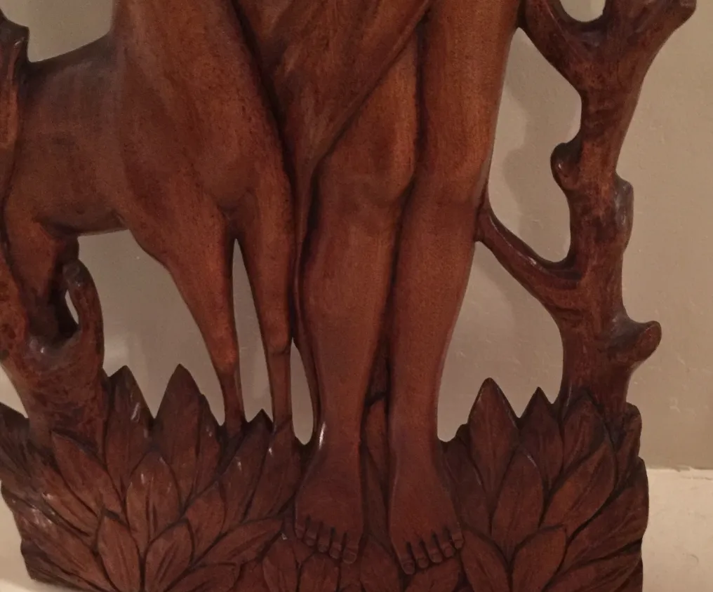 Antique wall plate featuring a stylized figure with decorative details in the background.