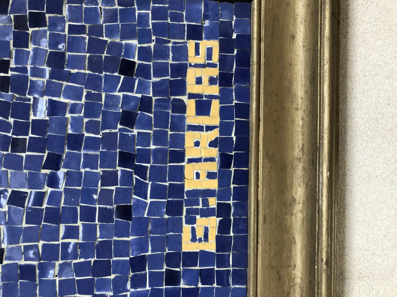 Quadro a mosaico antico con piastrelle blu e gialle, ambiente classico.