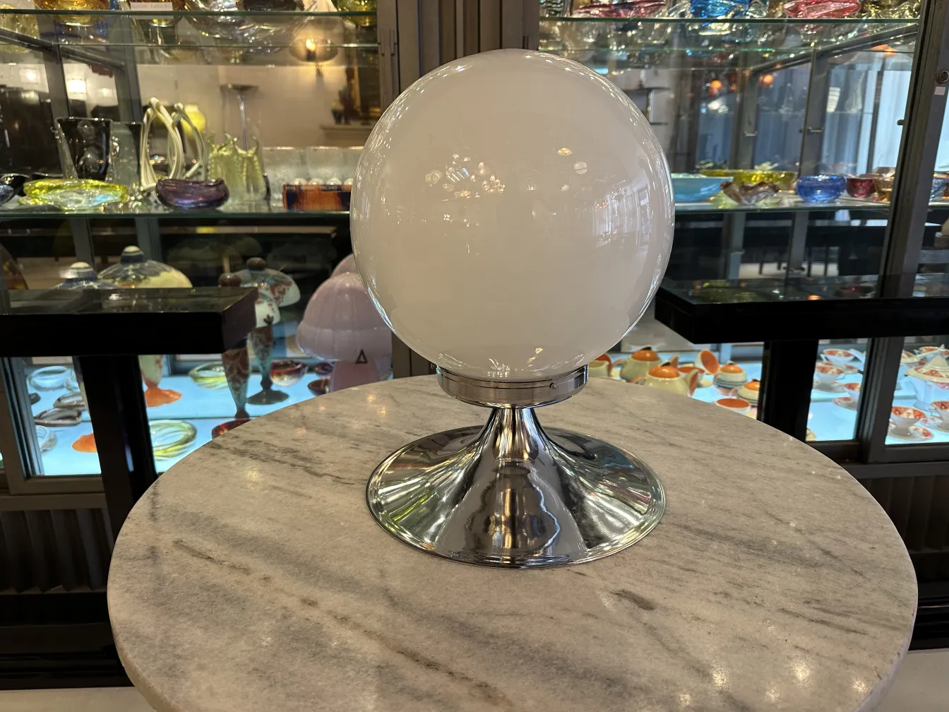 two antique table lamps with spherical shape and shiny base, showcase background with antique items