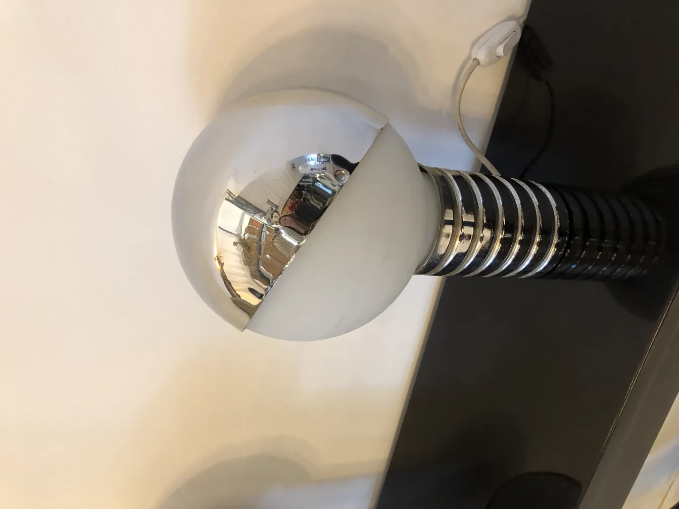 Due lampade da tavolo antiche in un ambiente caldo, con base argentata e paralume sferico bianco.