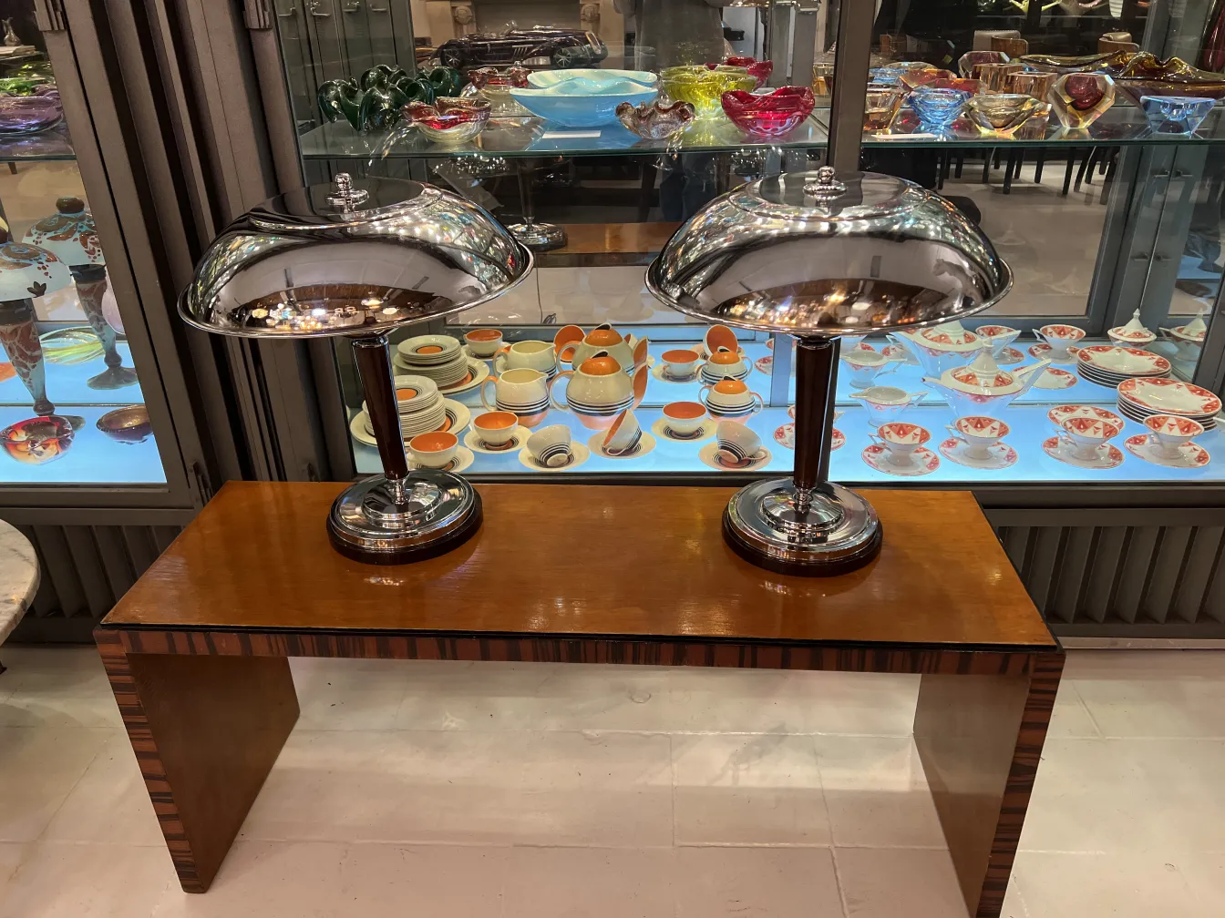 Duas lampadas de mesa antigas com acabamento brilhante em um ambiente antiquário.