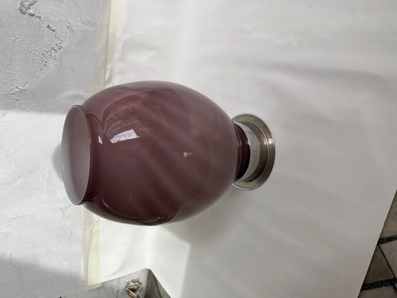 zwei antike Tischleuchten mit Metallbasis und burgunderfarbener Farbe auf einer weißen Oberfläche.