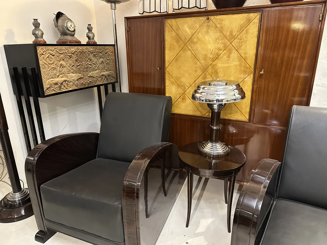 Dos lámparas de mesa antiguas en un entorno elegante con sillones y decoración de fondo.