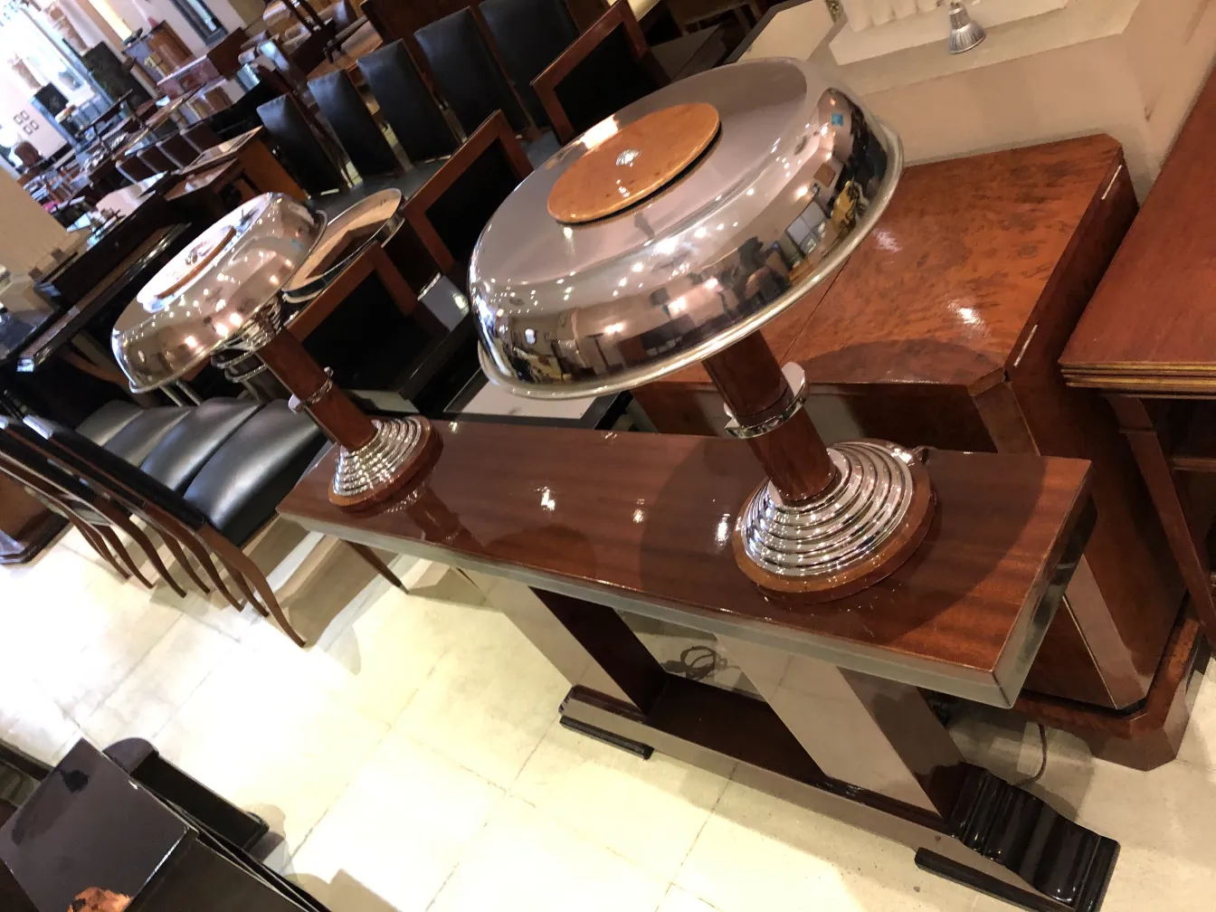 dos lámparas de mesa antiguas con bases brillantes, en un ambiente elegante, rodeadas de muebles vintage