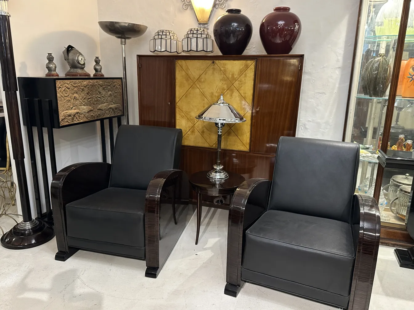 Due lampade da tavolo antiche in un ambiente elegante con poltrone in pelle.