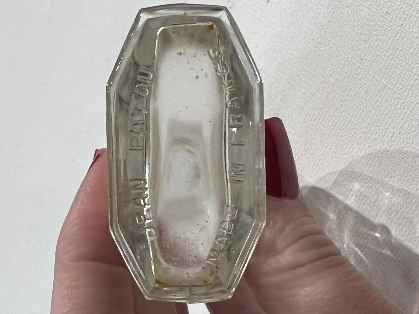 Flacone di profumo antico con dettagli in rilievo e segni di usura.