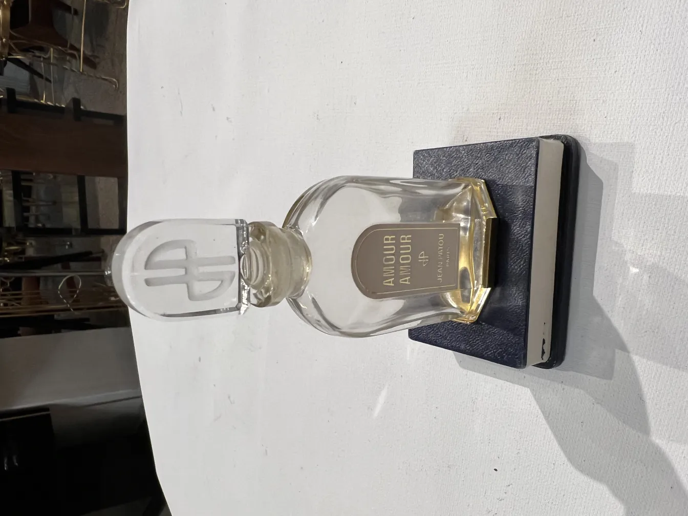 Flacon de parfum ancien avec un bouchon en verre distinctif sur une base bleue.