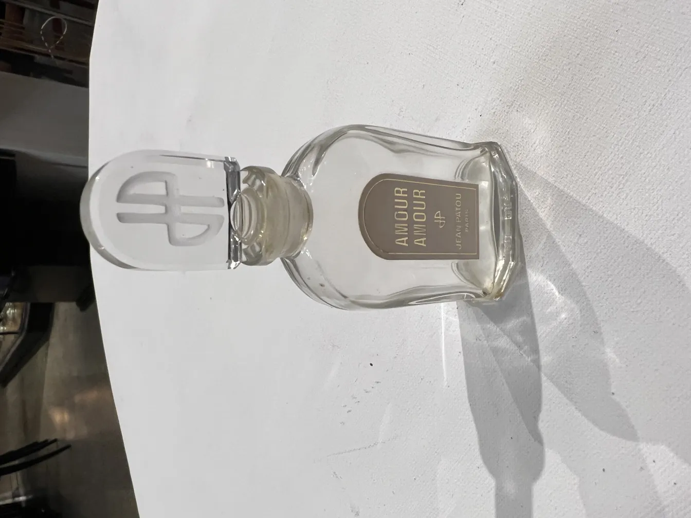 Frasco de perfume antigo com tampa de design em um ambiente neutro.