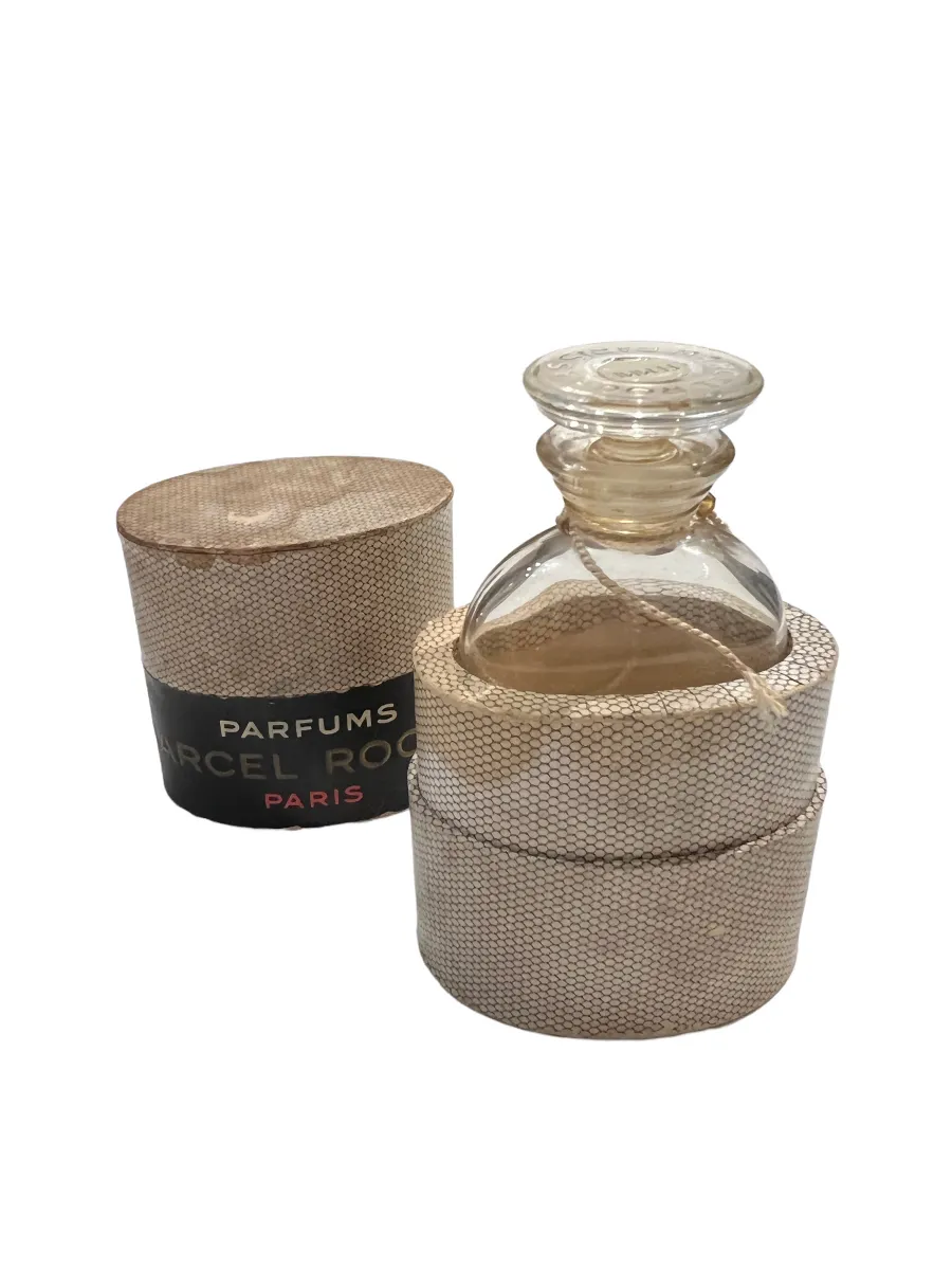 Antiguo frasco de perfume con tapa decorativa, envuelto con cuerda. Presenta un diseño elegante.