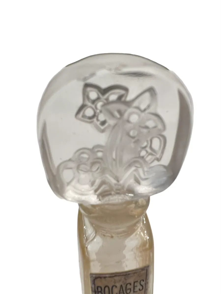 frasco de perfume antigo com desenho floral na tampa de vidro