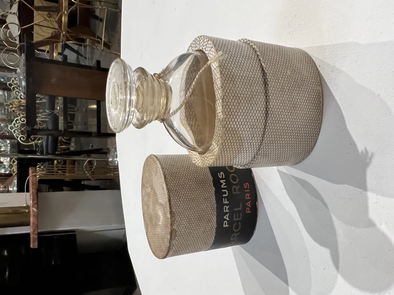 Frasco de perfume antiguo con estuche decorativo, elegantemente diseñado, en un ambiente nostálgico.