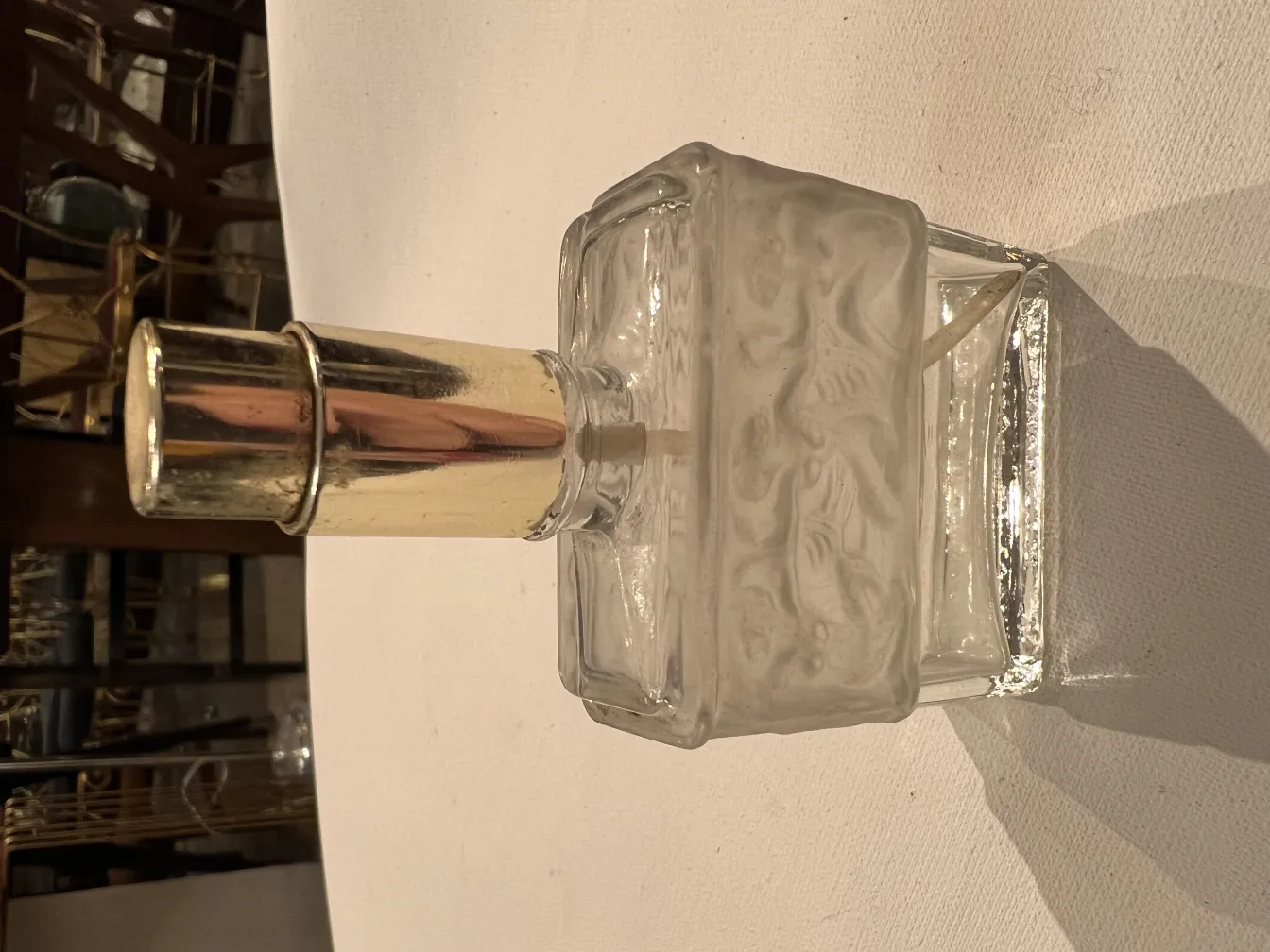 antique glass perfume bottle with shiny cap, decorated, on a white table.