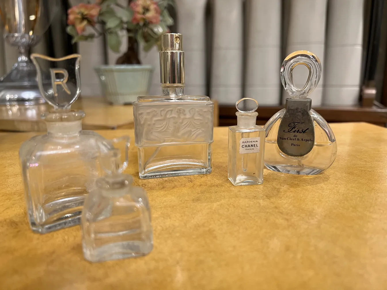 Vários frascos de perfume antigos sobre uma mesa de madeira, com formas e detalhes distintos.