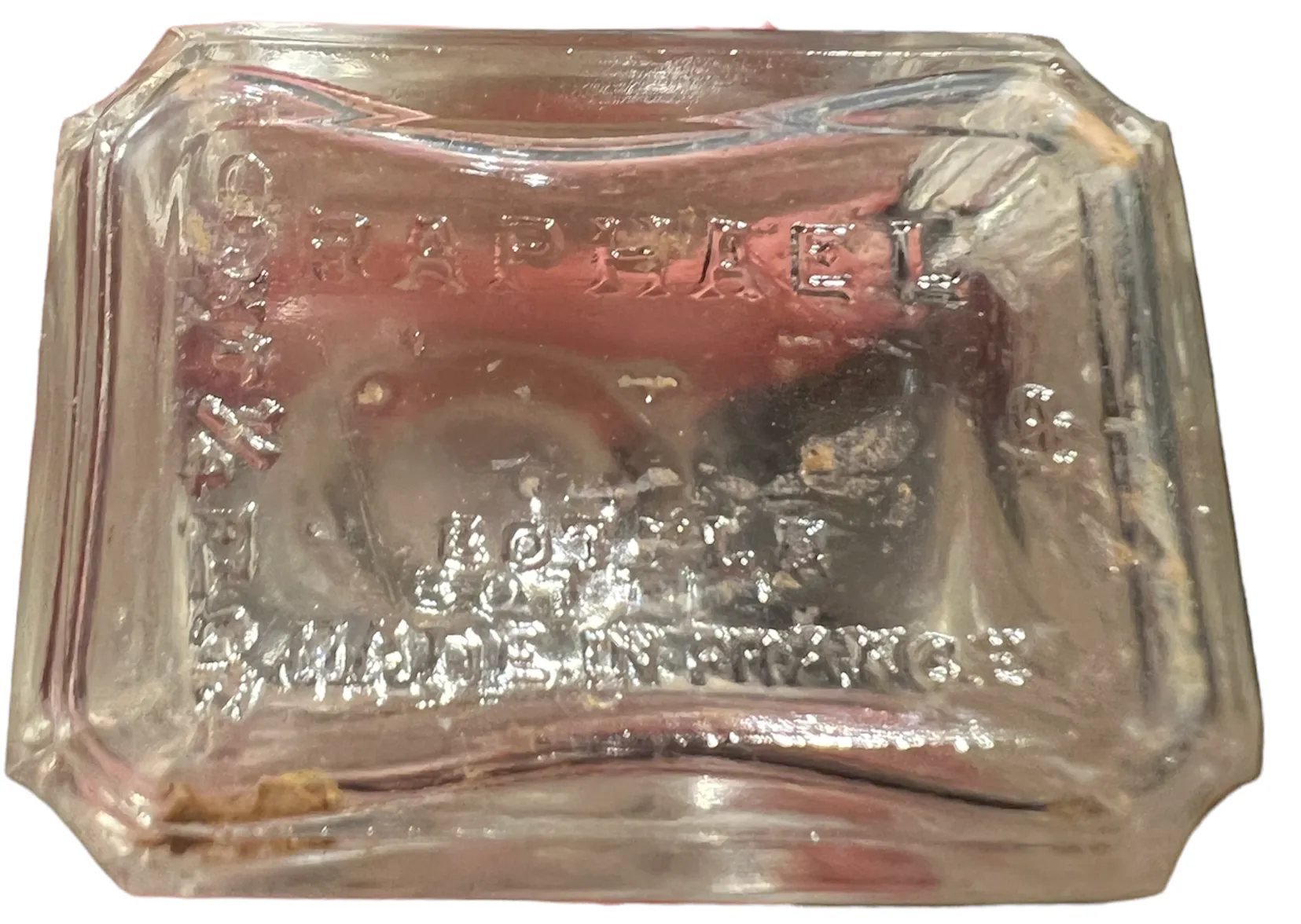 Antike Parfümflasche mit sichtbarer Inschrift, helle Farbe.