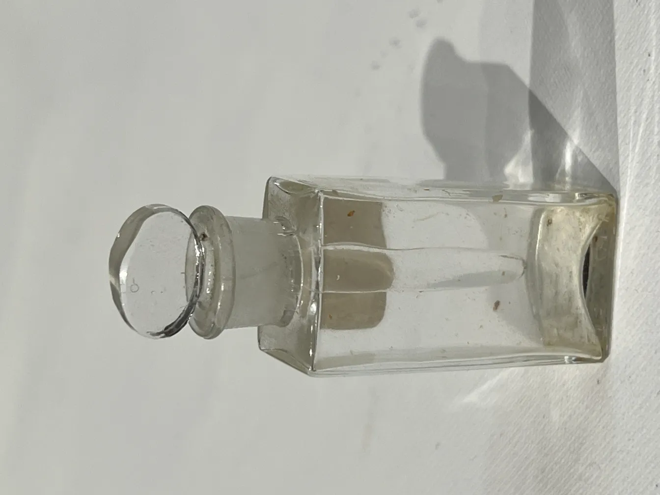 flacone di profumo antico con tappo rotondo e forma rettangolare