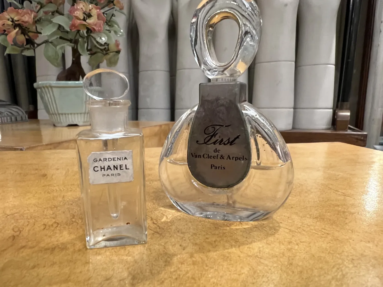 dos frascos de perfume antiguos, uno de Chanel y otro de Van Cleef, sobre una mesa