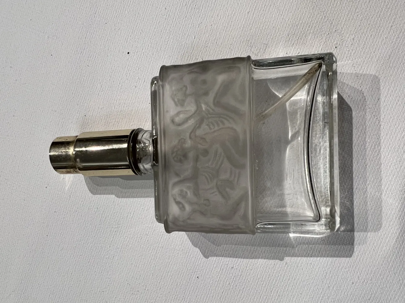 antike Parfümflasche mit Reliefdetails, elegant mit Metallkappe, vor weißem Hintergrund