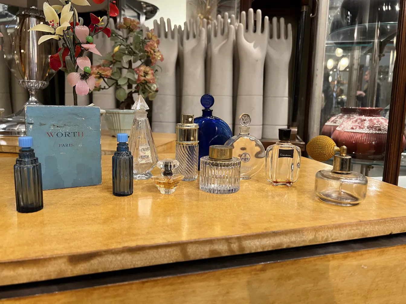 Frascos de perfume antigos decorativos sobre uma mesa de madeira, com várias cores e formas.