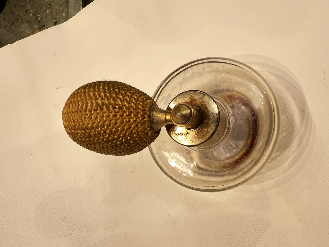 frasco de perfume antiguo con forma ovalada y atomizador dorado