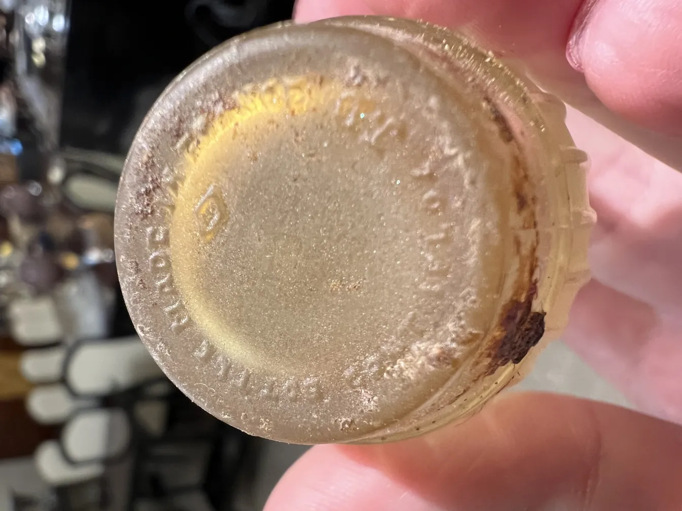 Flacon de parfum ancien avec des détails au fond, couleur dorée, aspect usé.