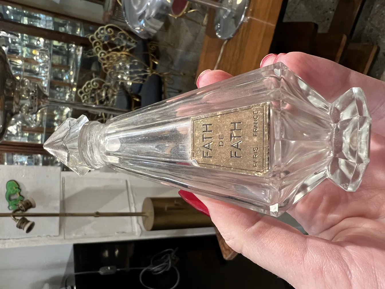 Antiguo frasco de perfume con diseño elegante, marca Fath, fondo de brillos.