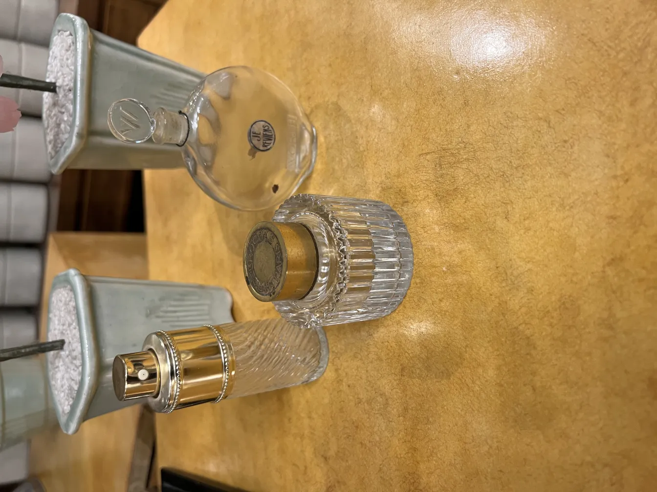 Três frascos de perfume antigos em uma mesa de madeira