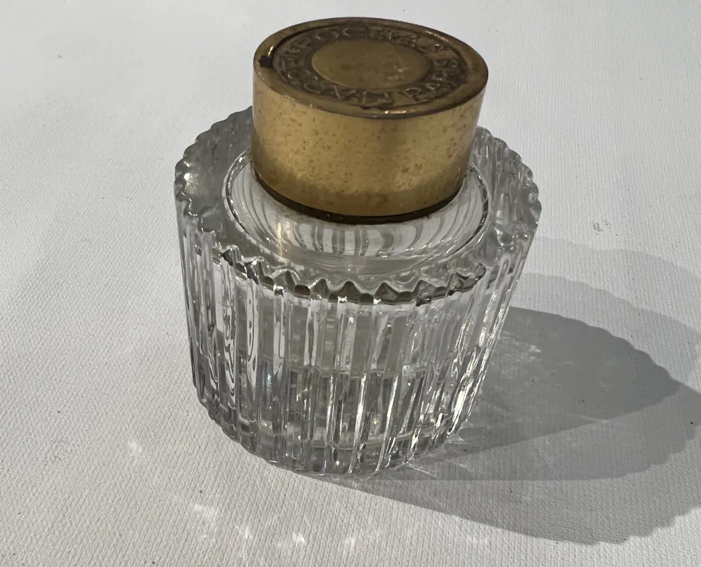 antique transparent perfume bottle with golden cap, intricate detailing and subtle shadows