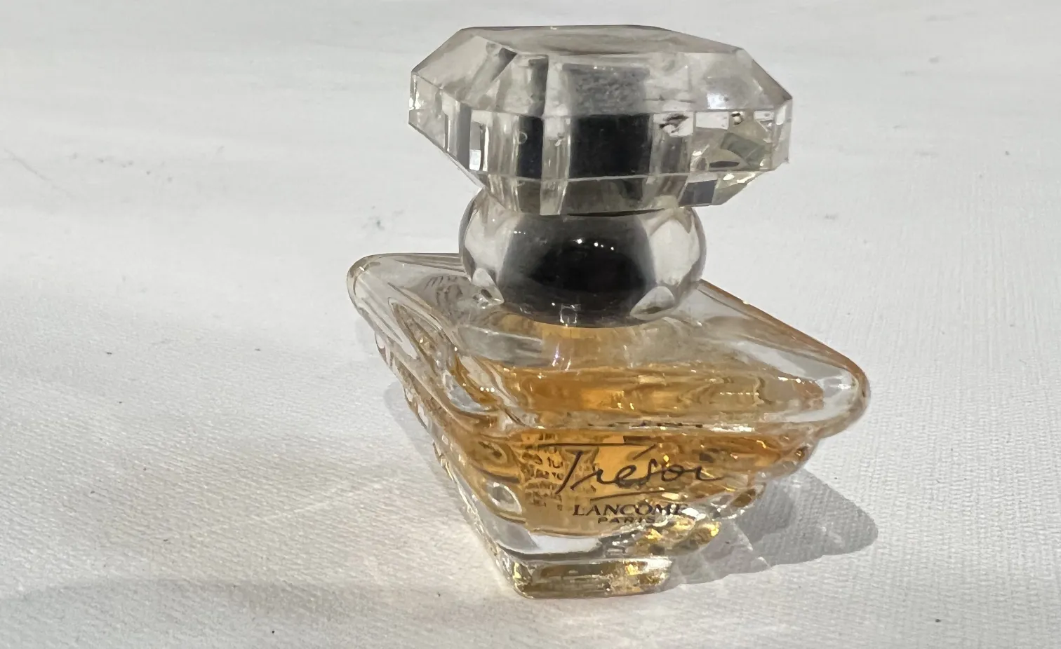Flacone di profumo antico Lancôme con tappo sfaccettato e liquido dorato