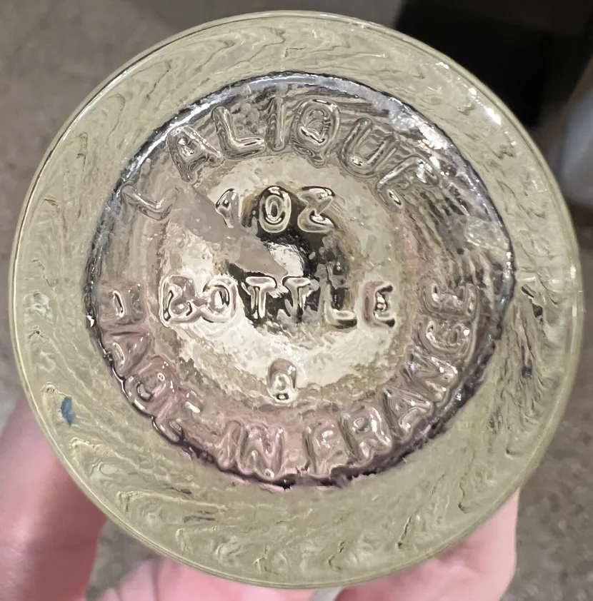 Antike Parfümflasche mit Inschrift am Boden, die klare Details und Umgebung zeigt.