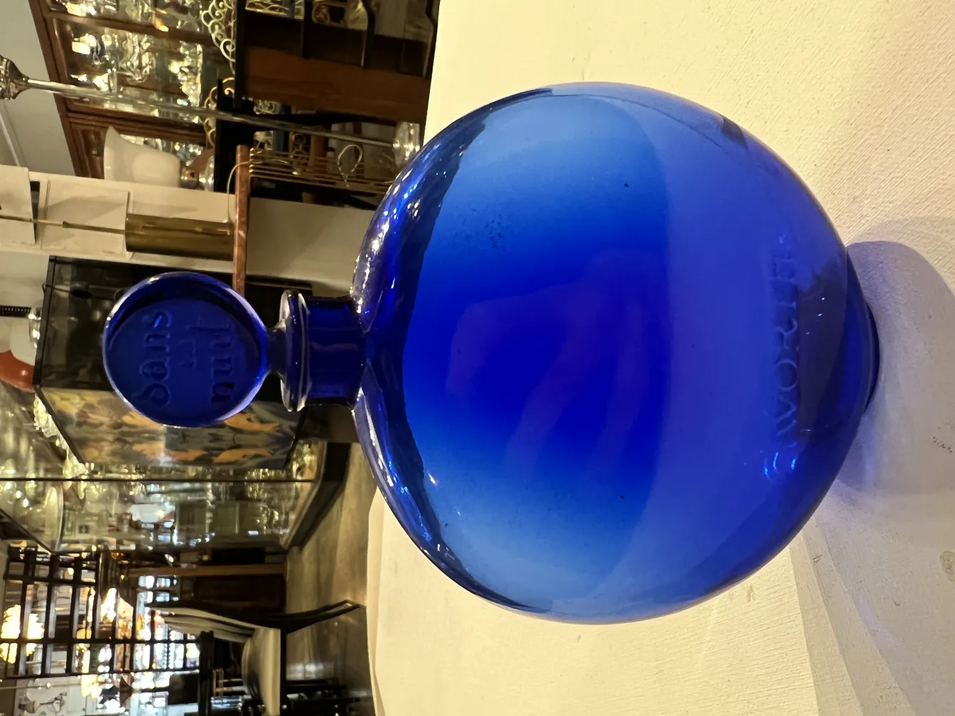 frasco de perfume antigo azul, forma redonda e tampa distinta, ambiente de antiguidades.