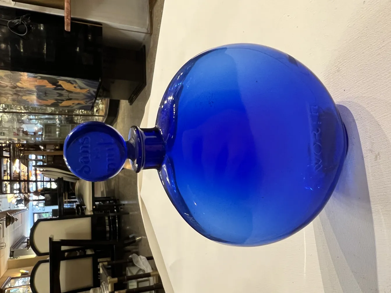 frasco de perfume antiguo de color azul, redondeado y elegante, en un entorno clásico