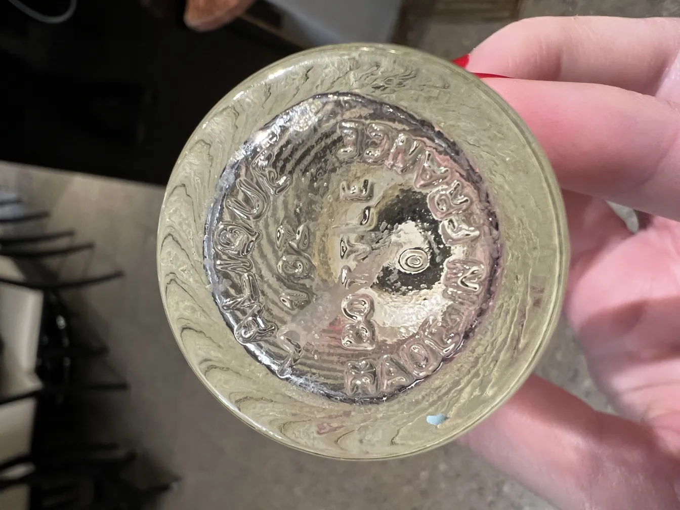 Flacon de parfum ancien avec design élégant et motif ondulé à la base, présenté dans un cadre neutre.