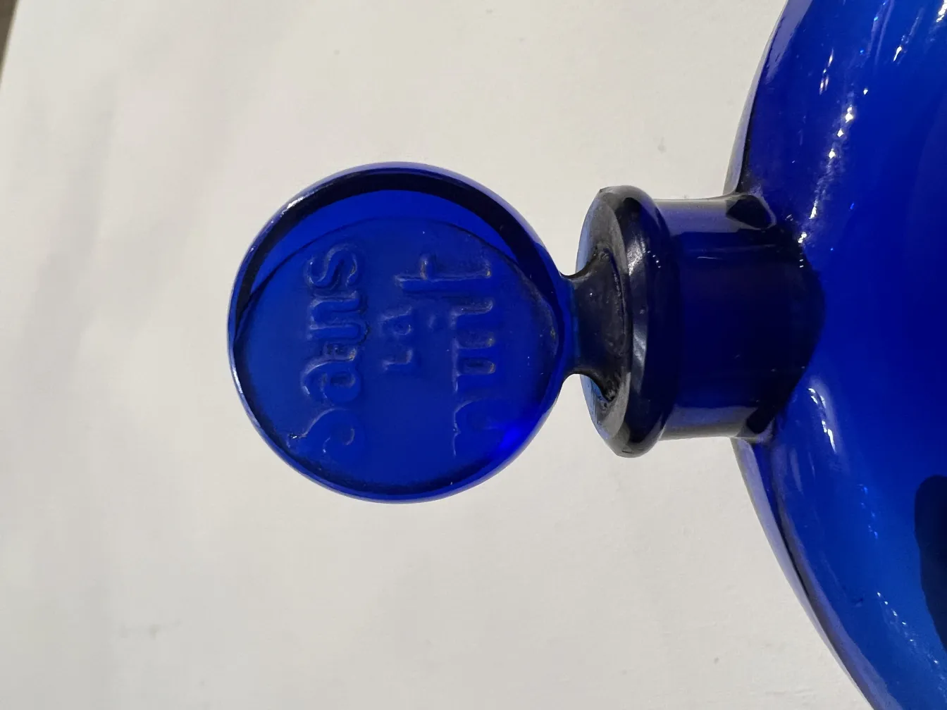 Frasco de perfume antigo azul com tampa redonda, base lisa.
