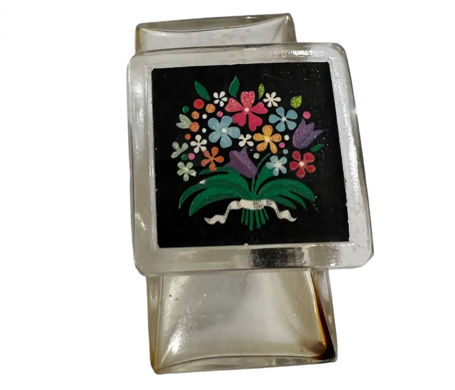 Frasco de perfume antiguo con dibujo colorido de flores sobre fondo negro, decoración alegre.