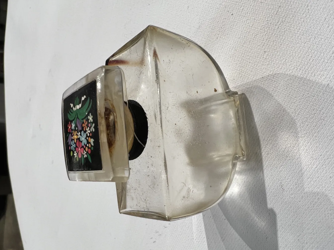 زجاجة عطر قديمة مع غطاء مزخرف وتصميم أزهار