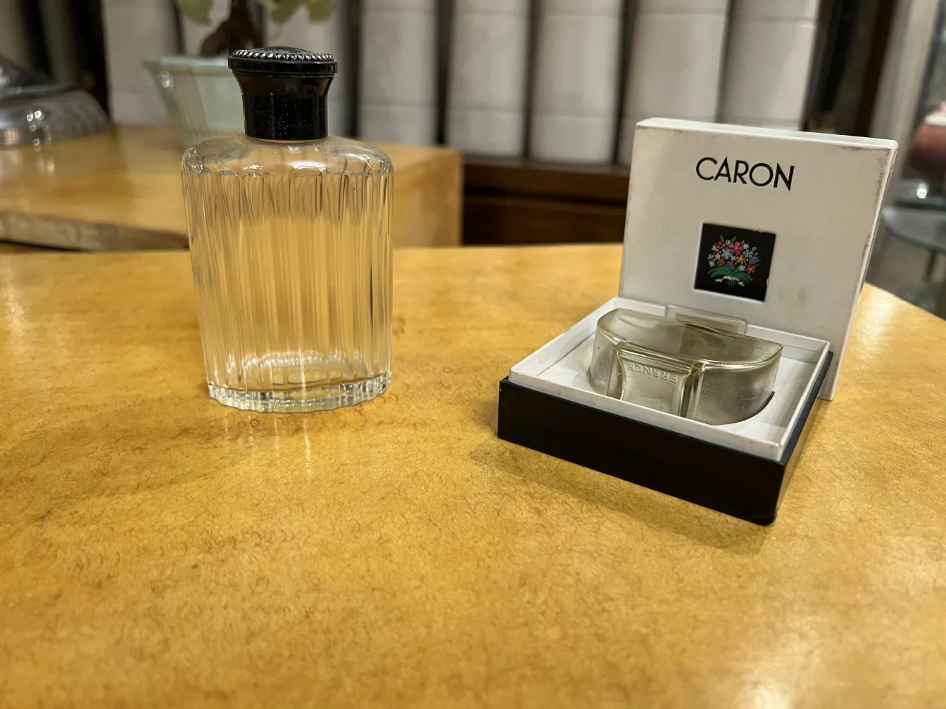 frasco de perfume antigo com tampa preta em ambiente rústico