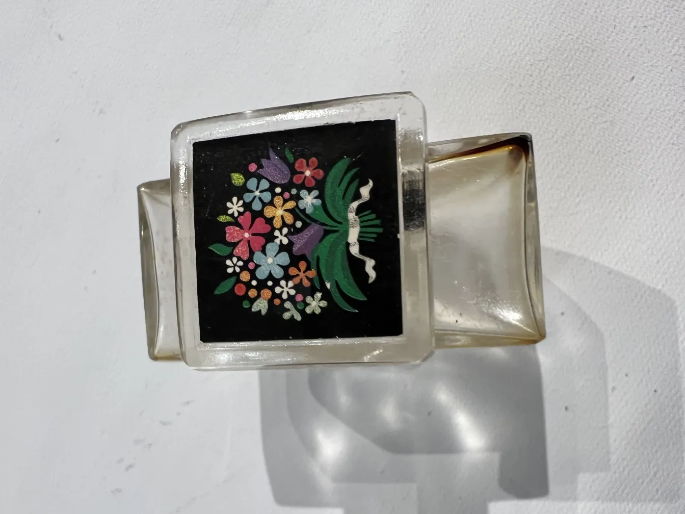 flacon de parfum ancien avec des fleurs sur fond noir