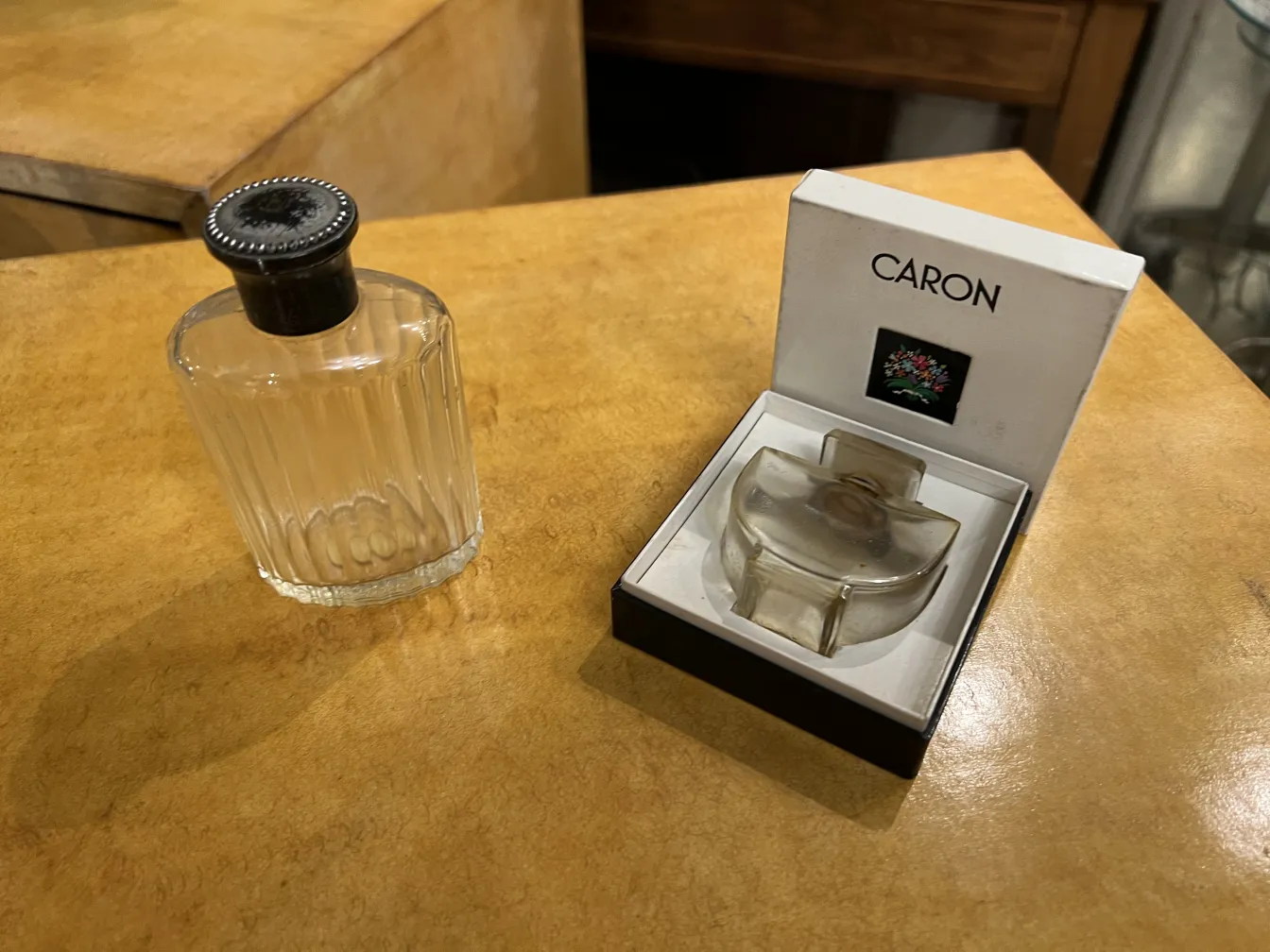 antique perfume bottle with black cap, situated on wooden surface