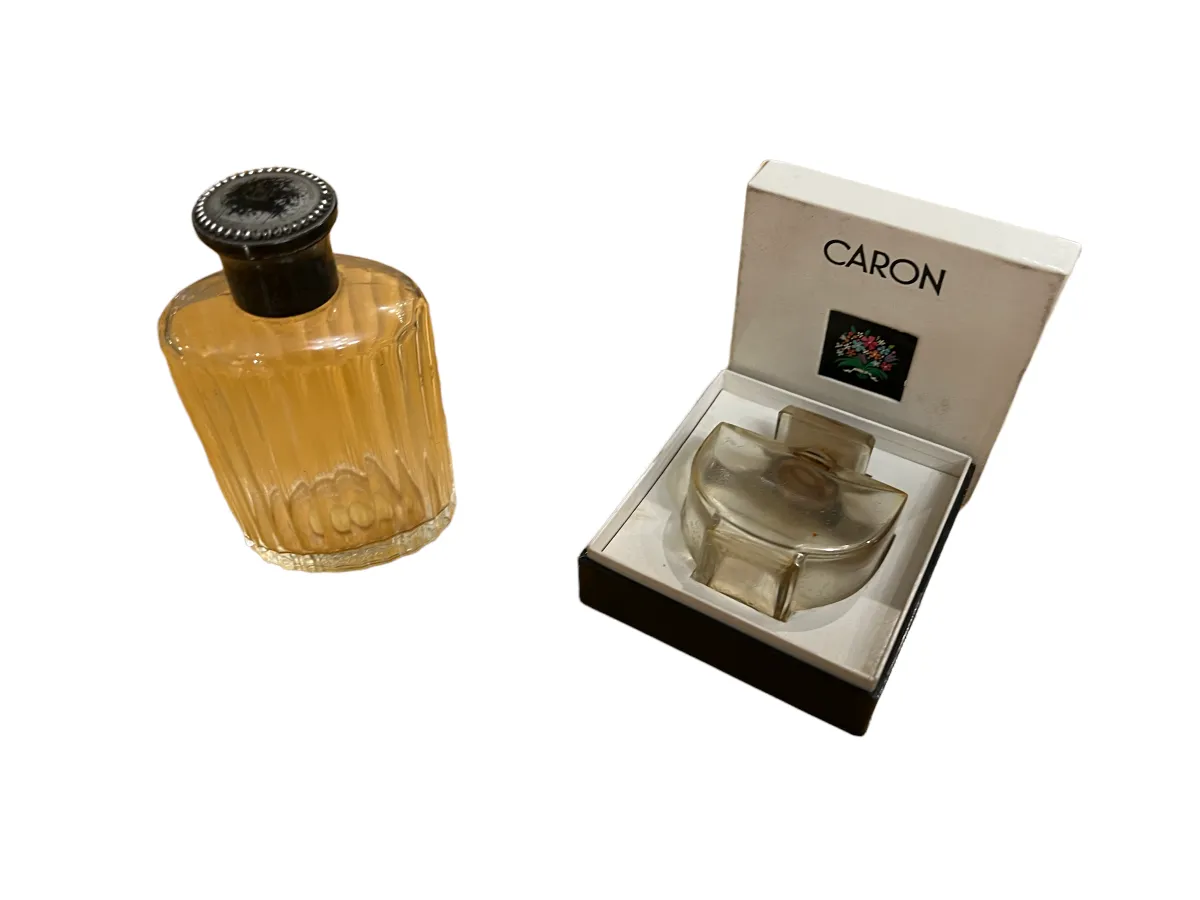 frasco de perfume antiguo decorado con líneas verticales, tapa negra, presentándolo junto a su caja