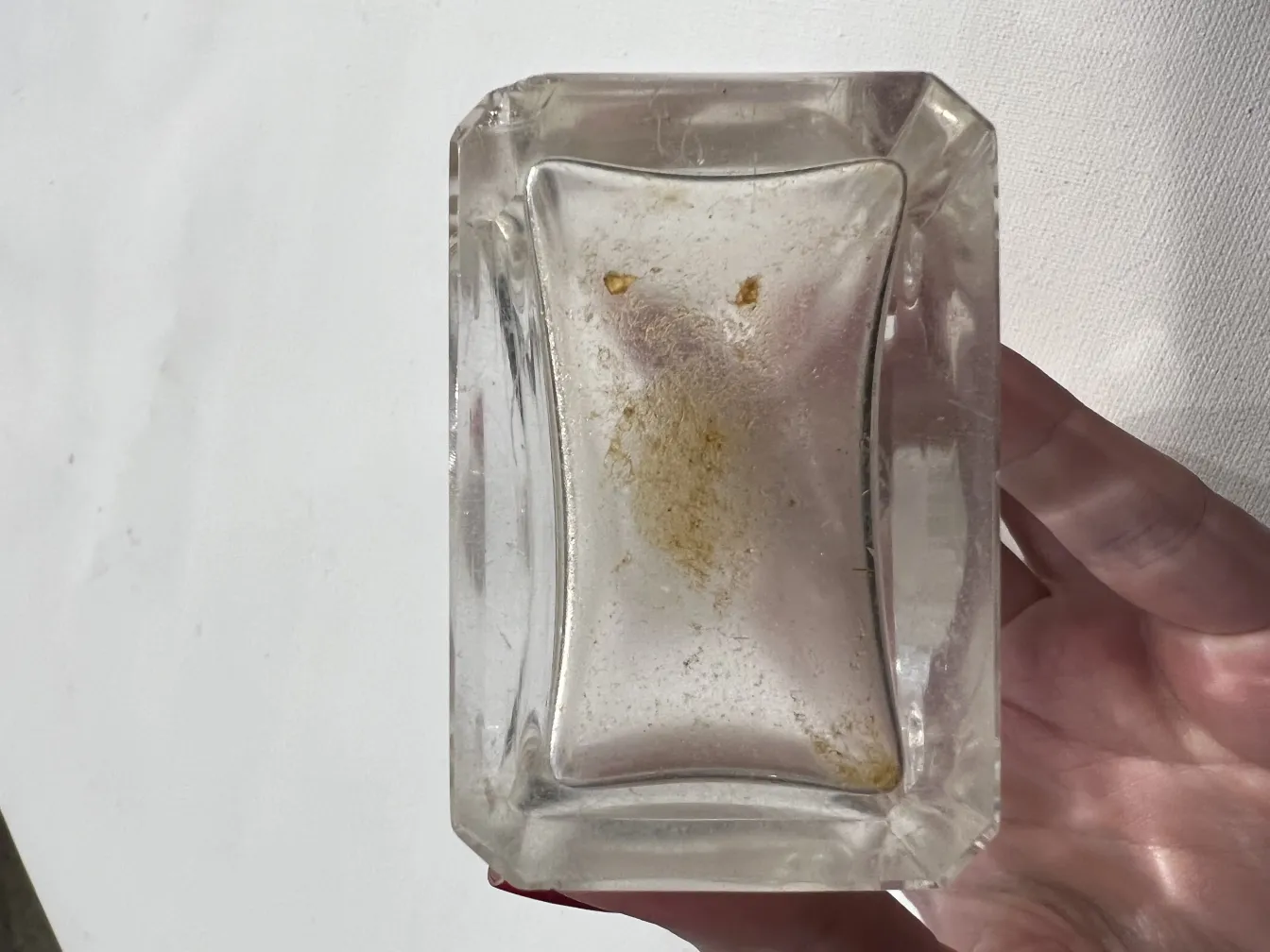 frasco de perfume antiguo, con forma rectangular y detalles sutiles, un brillo tenue