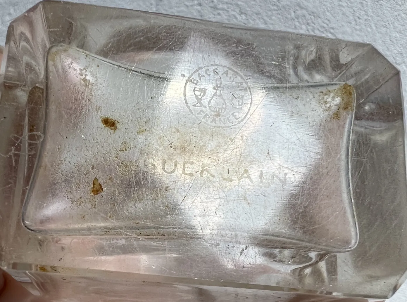 Flacone di profumo antico in forma rettangolare, trasparente, con segni di usura.