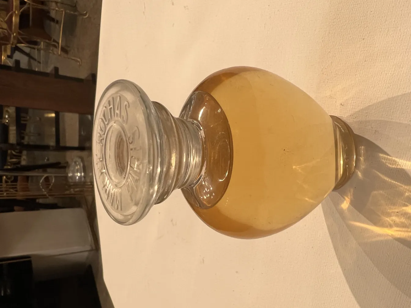 flacon de parfum ancien avec liquide doré et bouchon clair sur fond clair