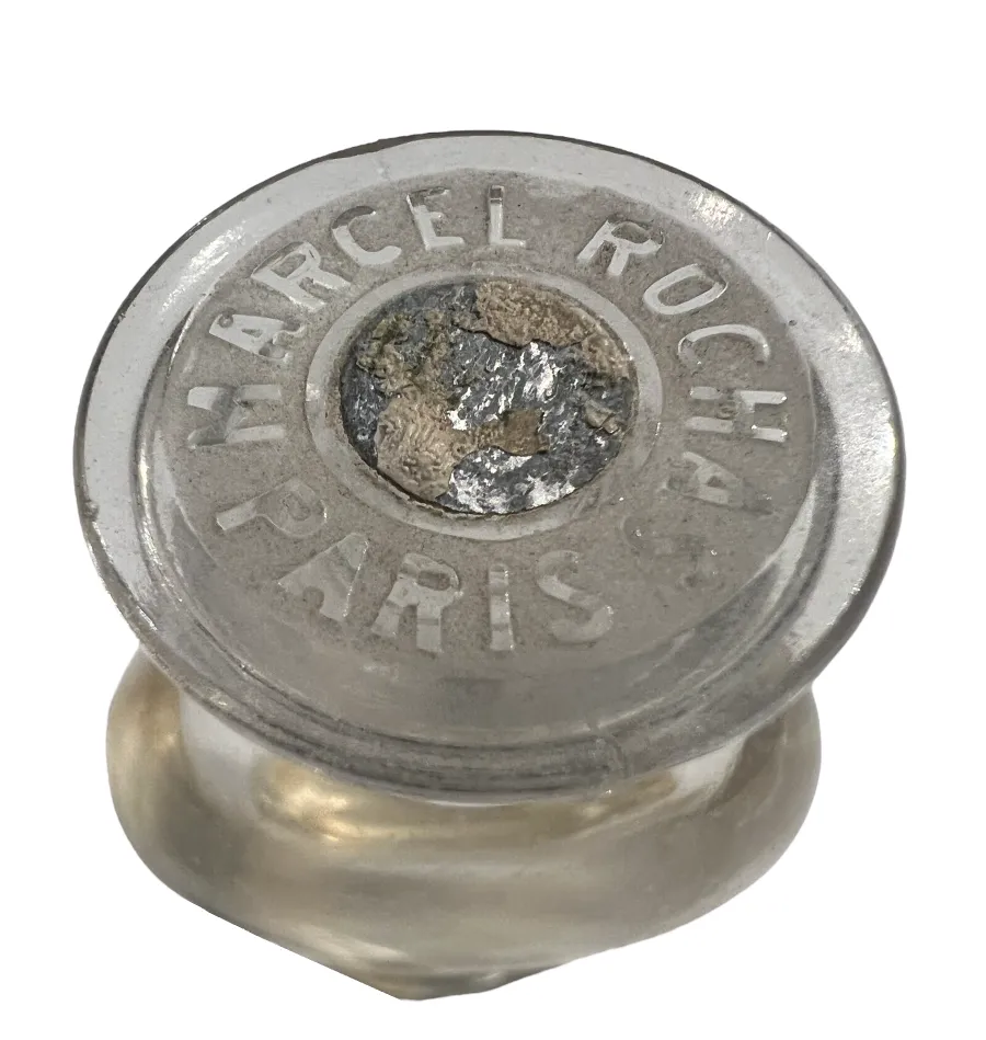 frasco de perfume antigo com tampa marcada e detalhes visíveis.