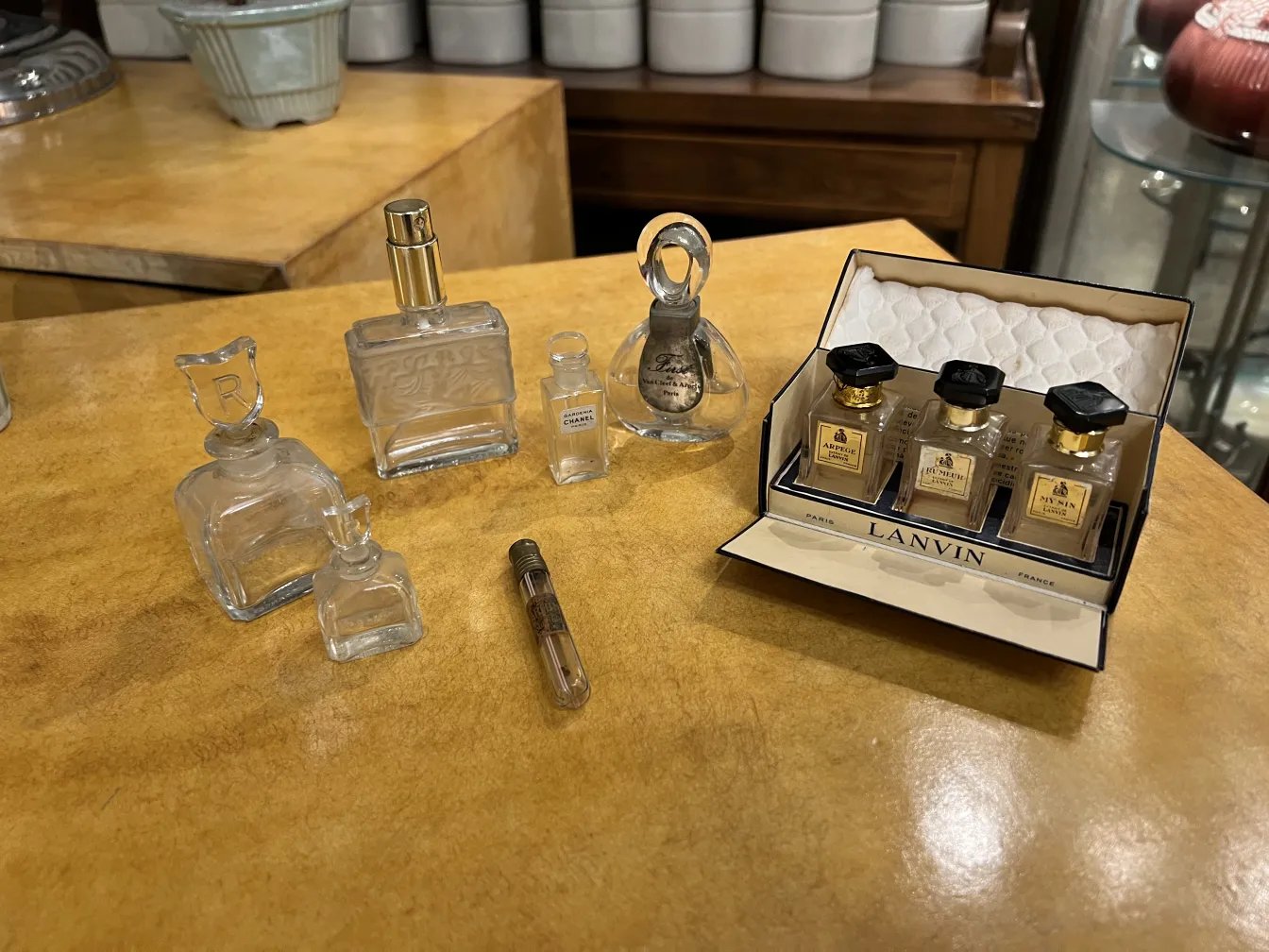 عدة زجاجات عطر قديمة في مجموعة زخرفية على سطح خشبي فاتح.