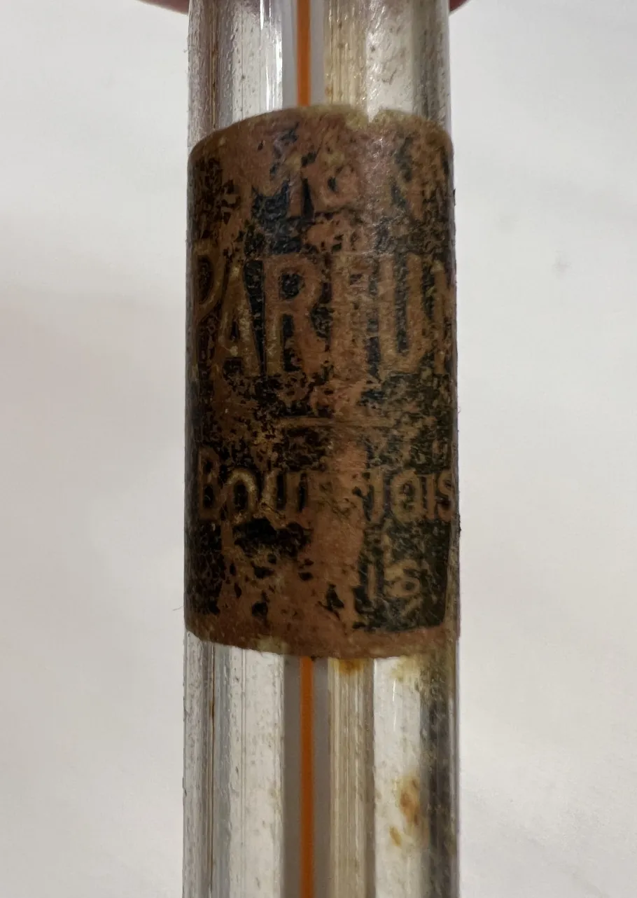 frasco de perfume antigo com etiqueta danificada e poeira