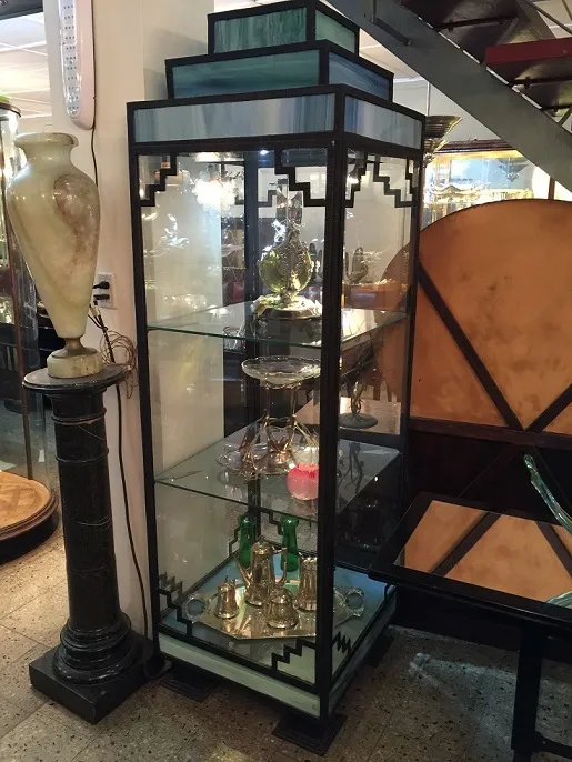 Antike Vitrine mit dekorativen Objekten und beleuchtetem Hintergrund.