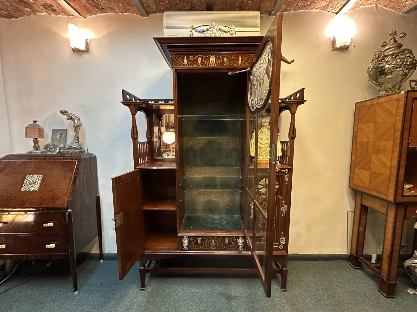 Antique display cabinet with artistic details and decorative items around.